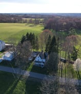 Aerial view of a large farm in the country, featuring a vast field of grass and scattered trees