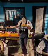 hazema in a baseball cap by a audio recording studio desk