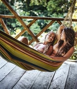 Dos amigas mirándose mientras descansan en una hamaca