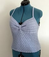 Top d'été tricoté avec un fil coton bleu clair il est posé sur un mannequin de couturière 