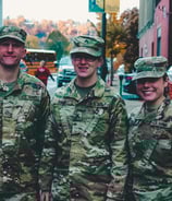 Male and female military in camoflage uniforms standing together in a town plaza