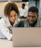 a man and woman looking at a laptop computer