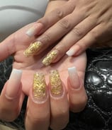 Imagen de manos con uñas decoradas con detalles dorados: