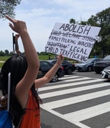 Woman holding sign that says, "Abolish family policing industry and legal child trafficking."