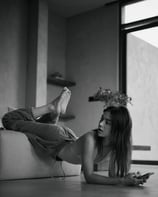 A woman relaxes on a couch with feet up, captured at Casa Wabii by Theodorous Yuvens.