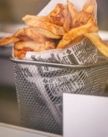 Golden fries wrapped in paper, gently placed in a sleek sieve, capturing the essence of a restaurant