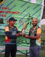 a man holding a trophy in front of a banner