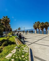 a bench with people sitting on benches near the water