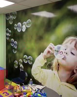 Custom graphics of a little girl blowing bubbles for a children's play area at a car dealership