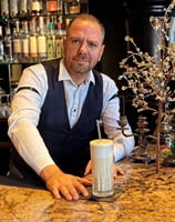 a man in a vest and vest is holding a drink