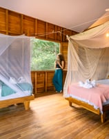 woman looking out of her window in wooden bungalow retreat center