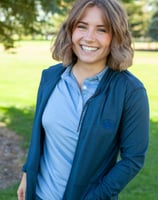 a woman in a blue jacket and jeans standing in a field