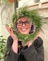 a woman holding a wreath of pine needles