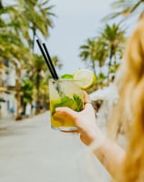 Cóctel mojito refrescante en la terraza de Santa Lola Badalona con palmeras de fondo.