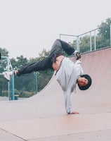 YoYo performing a breakdance freeze in a skateboard park.
