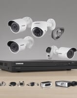 A close-up view of the back of a server rack with multiple network cables connected to a switch. The cables are in different colors including white, orange, black, and light blue. There are also various ports, indicators, and a digital display indicating some operational parameters.