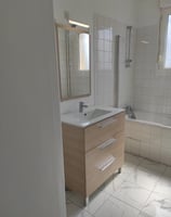 installation dans une salle de bain d'un nouveau lavabo avec son meuble, miroir et éclairage