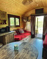 Intérieur de la roulotte avec un des jolis canapé en bois, télé, table à mangé