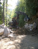 spider hoe being used for building a rock retaining wall