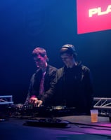 two men standing in front of a dj booth