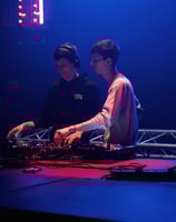 two men standing in front of a stage with a dj and a dj