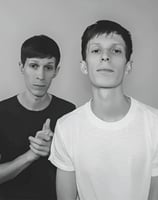 two men standing next to each other in front of a wall