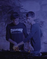 two men standing in front of a wall with a dj booth