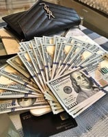 a purse with money and a purse on a bed