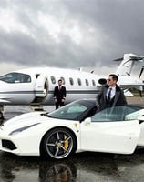 a man in a suit and tie standing next to a white car