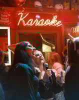 a woman singing into a microphone while standing in front of a karaoker