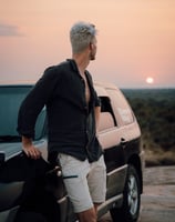 a man standing next to a car watching the african sun