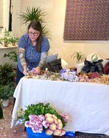 a woman is standing in front of a table with flowers