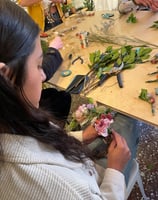 a woman is making a flower arrangement for a wreath