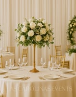 Luxury event planning setup with round tables, white linens, golden Chiavari chairs, and floral centerpieces in an elegant se