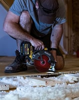 Handyman using a circular saw to cut subflooring during floor framing repair