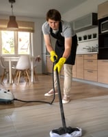 a man in a black apron and yellow gloves cleaning a floor