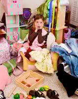 a girl sitting on a chair in a messy room