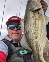 a man holding a large fish on a kayak