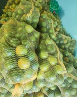 Laranjas ensacas em sacos de linha amarela. Frutas vistosas e de excelente aparência.