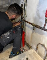 a man in a black shirt is fixing a pipe