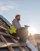 un ouvrier en rénovation énergétique construit une toiture