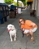 a woman in a orange shirt is holding a leash and a dog