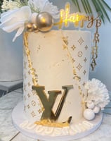 a cake with a gold foil lettered on top of a table