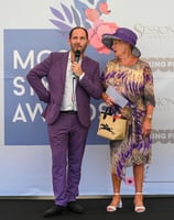 Alex in purple suit with well-dressed lady in purple hat