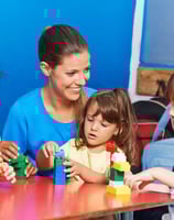 a woman and two children playing with blocks