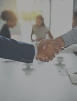 two people shaking hands in front of a table