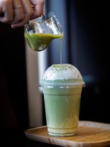 a person pouring a drink into a cup