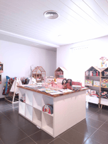 Aménagement du magasin de jouets avec des étagères et un plan de travail en bois et murs blancs
