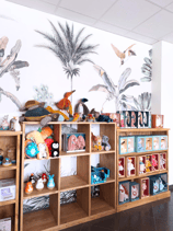 Magasin de jouets avec des mobiliers en bois du papier peint fleuri et des peluches