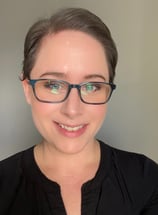 Photo of owner E. O'Hara of Main Street E-Market with black shirt and glasses and pixie cut hair